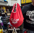 Person holding a red 'Custom Gripz' bag in a workshop setting