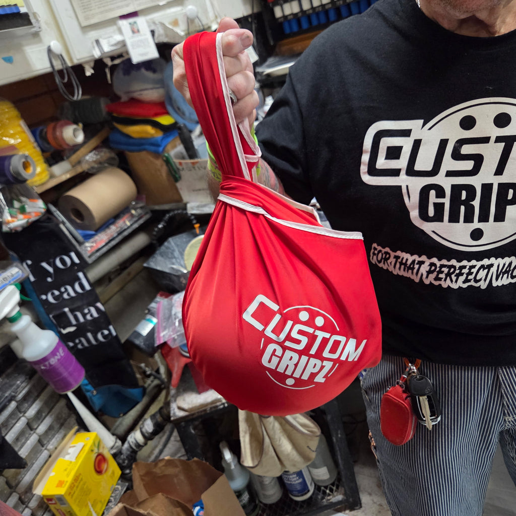 Person holding a red Custom Gripz bowling ball buffer bag in a workshop setting